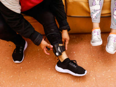 Faustina Alvarado Garcia (left) sits next to her daughter Madelin Souza Alvarado, 11, as she adjusts her ankle monitor in the community room at Hamilton shelter in San Francisco, California, on June 18, 2019. Her ankle monitor was put on her by immigration and has been causing her pain.