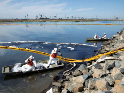 Workers with Patriot Environmental Services clean up oil that flowed into the Talbert Marsh in Huntington Beach on October 3, 2021.