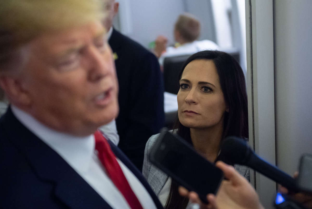 White House Press Secretary Stephanie Grisham listens as President Donald Trump speaks to the media aboard Air Force One on August 7, 2019.