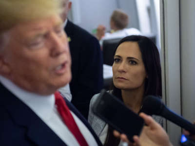 White House Press Secretary Stephanie Grisham listens as President Donald Trump speaks to the media aboard Air Force One on August 7, 2019.