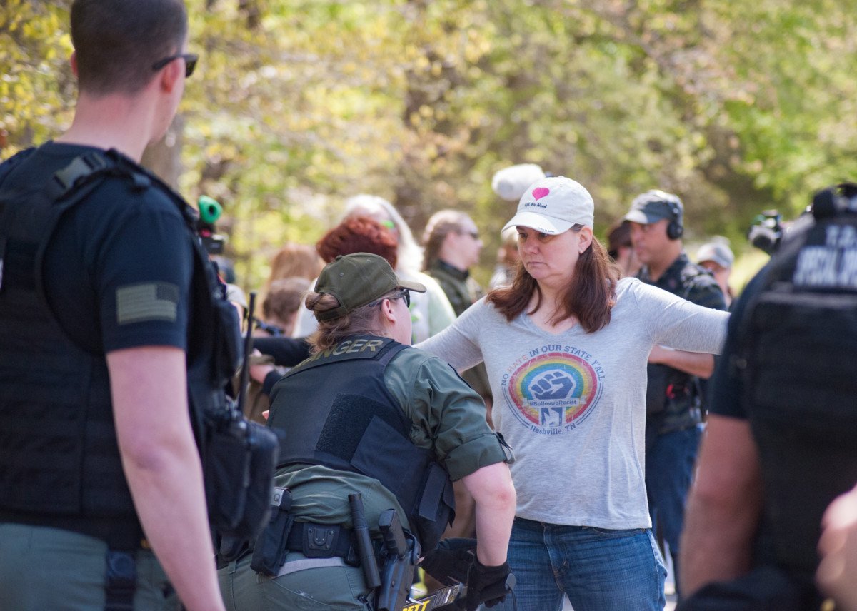 Police search a protester at the entrance to a designated protest area outside the 2018 American Renaissance conference in Burns, Tennessee.
