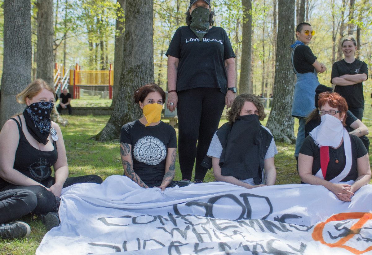 Activists don masks in response to police escorting a demonstrator out of the protest area for allegedly wearing a mask at a protest of the 2018 American Renaissance conference in Burns, Tennessee.