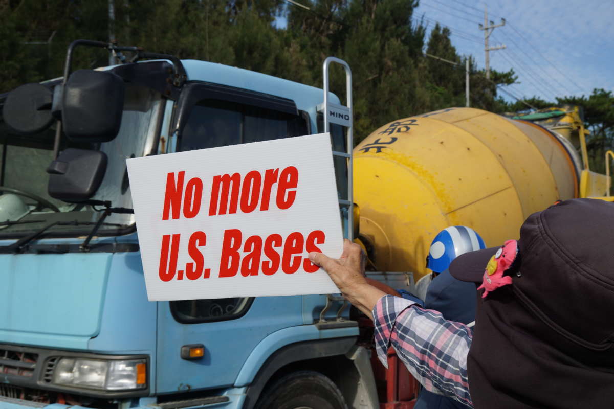 A protester holds a sign reading "no more us bases" during a protest