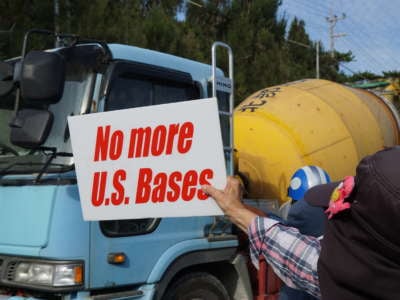 A protester holds a sign reading "no more us bases" during a protest