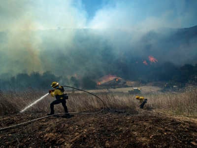 Los Angeles County Firefighters put out hot spot on a brush fire, estimated at 24 acres, in Westlake Village, California, on April 29, 2021.