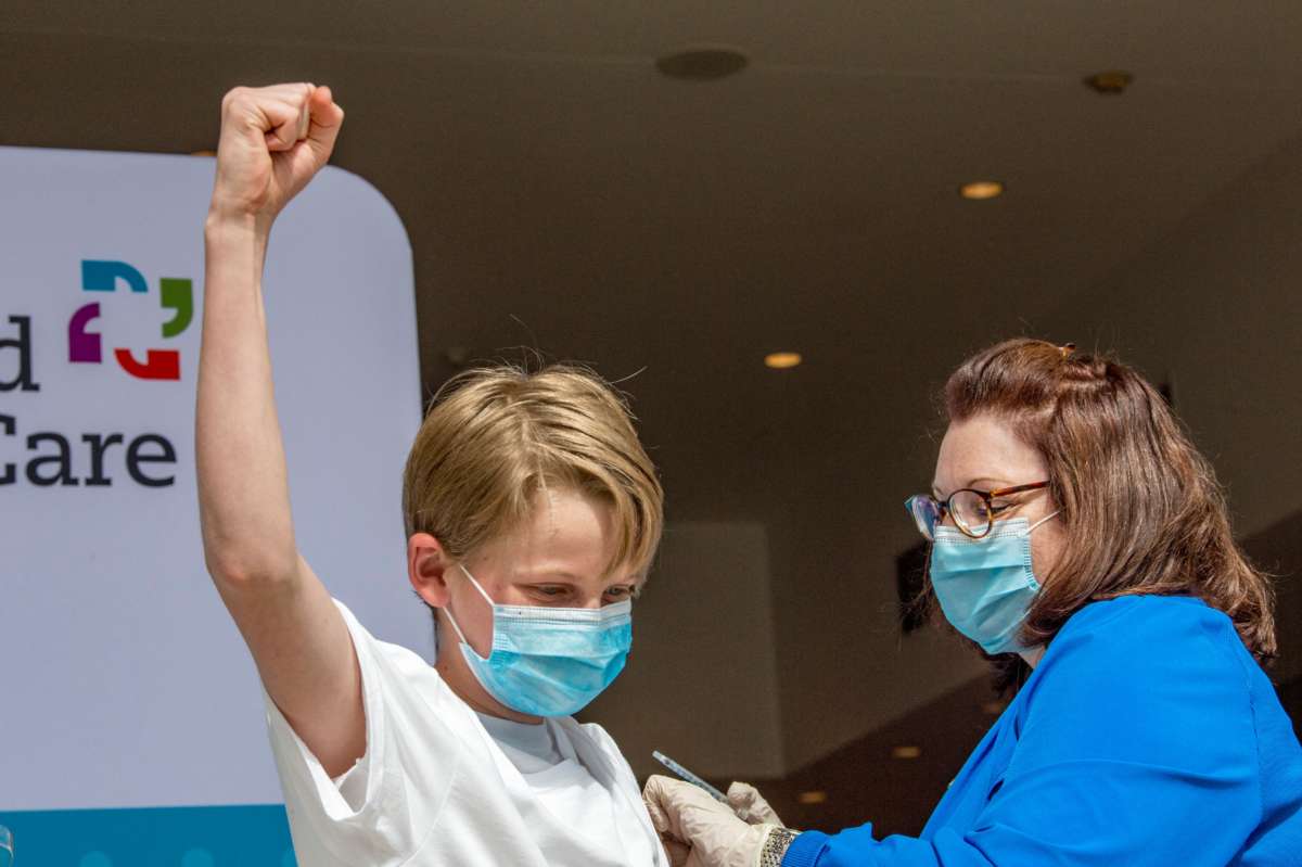 A boy pumps his fist while reciving the covid-19 vaccine