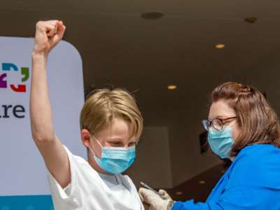 A boy pumps his fist while reciving the covid-19 vaccine