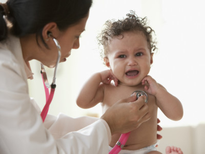 Doctor examining crying baby girl