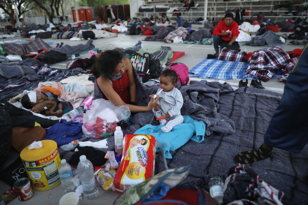 An immigrant mother gives medicine to her sick child after a night's rest on an outdoor basketball court during a pause on their journey toward the US-Mexico border on April 22, 2018, in Hermosillo, Mexico.