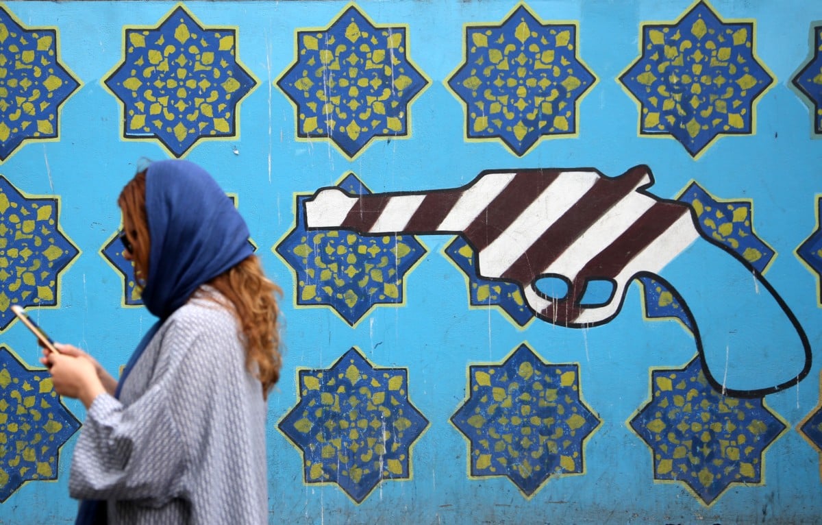 A woman passes a mural painted on the wall of the former US Embassy in Tehran, Iran.
