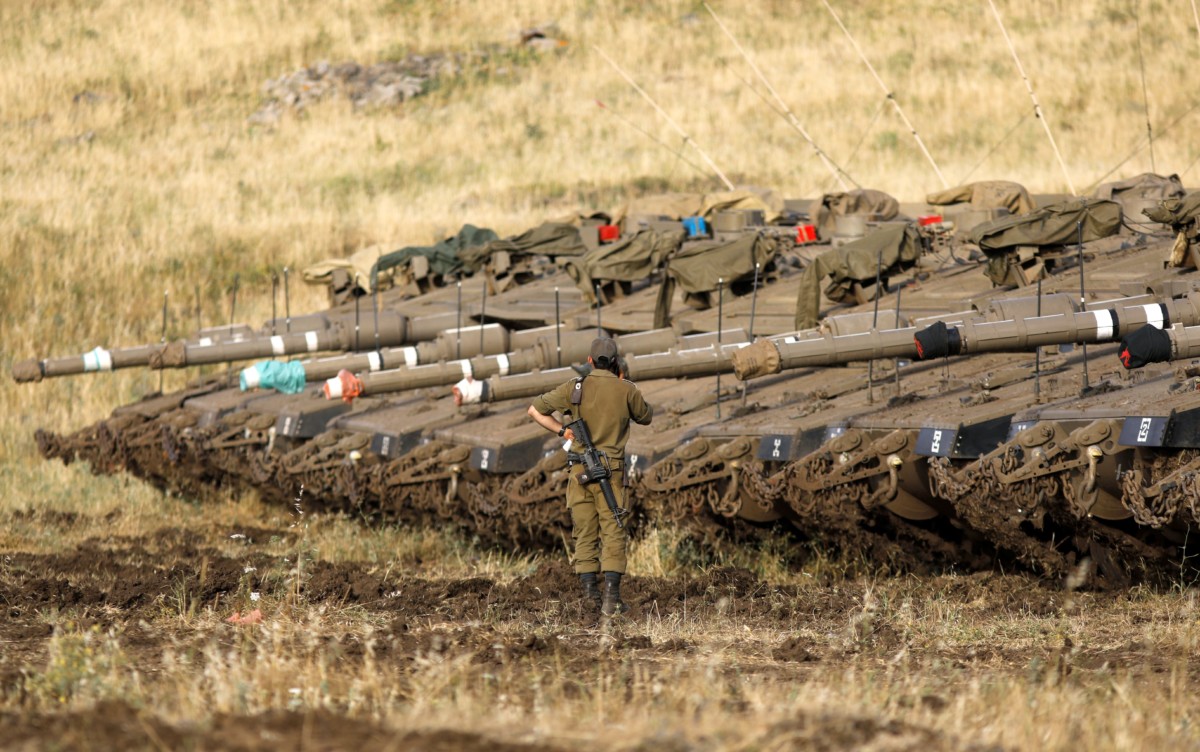 An Israeli soldier stands next to Merkava Mark IV tanks in a deployment area near the Syrian border in the Israel-annexed Golan Heights on May 10, 2018.
