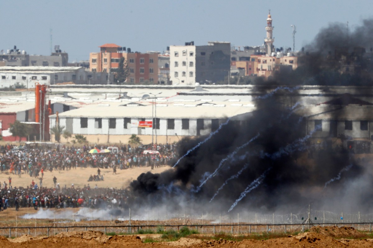 A picture taken on May 14, 2018, from the southern Israeli kibbutz of Nahal Oz across the border with the Gaza Strip shows tear gas canisters launched by Israeli forces falling down on Palestinian protesters gathering along the border fence with Israel. Dozens of Palestinians were killed by Israeli fire on May 14 as tens of thousands protested the US transfer of its embassy to Jerusalem.