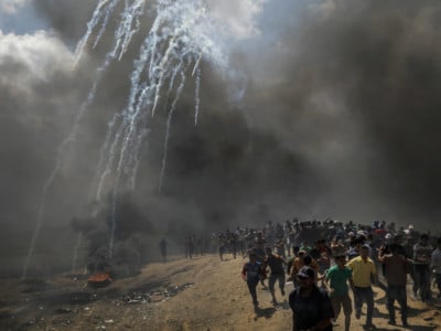 Protesters run away from tear gas dispersed by Israeli forces as they inch closer to the border fence separating Israel and Gaza on May 14, 2018, in a camp east of Gaza City, Gaza.