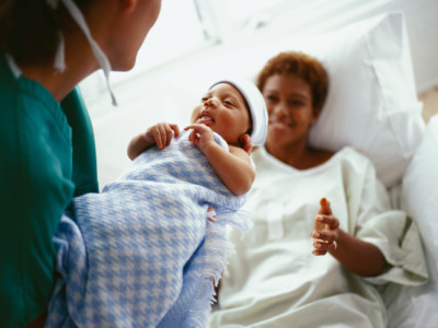 elevated close-up view of a doctor handing a new born baby to the mother