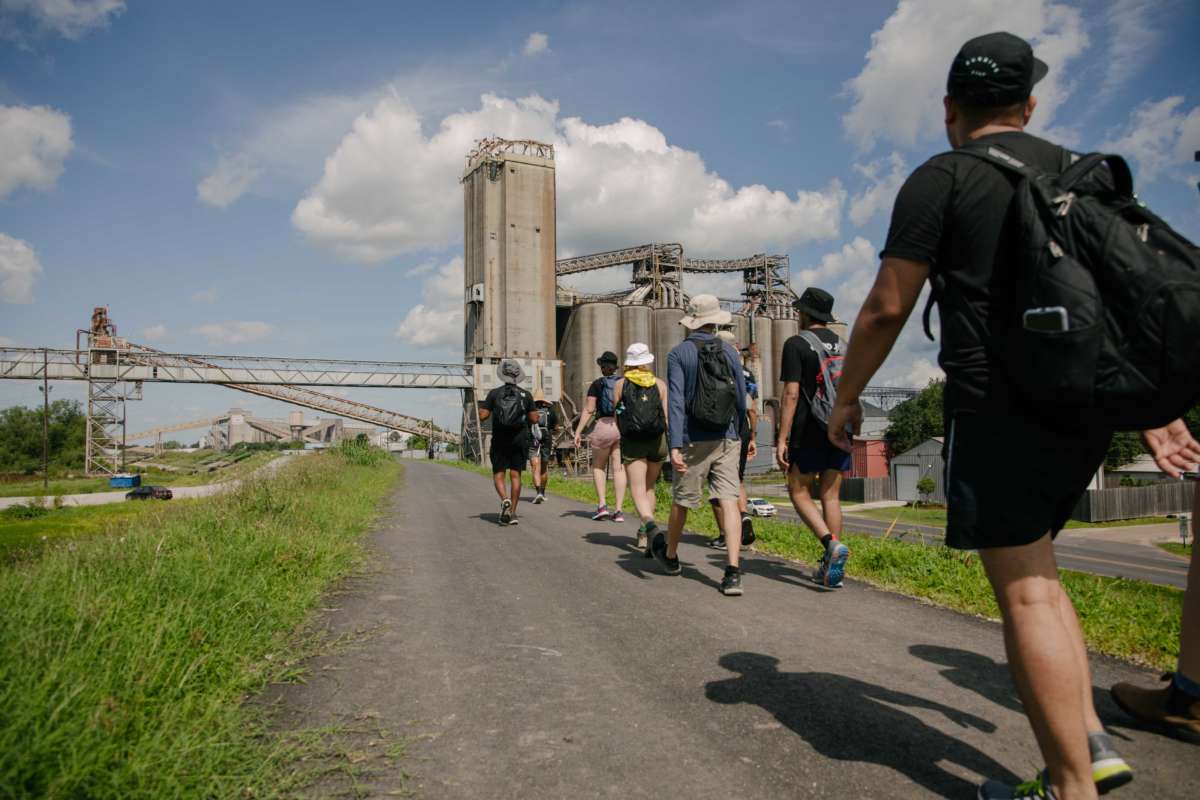 Sunrise Movement marchers walk along the Mississippi River past oil refineries.