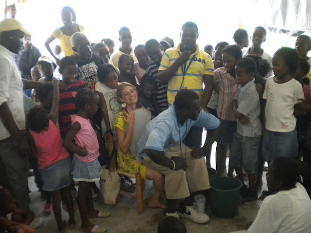 Sasha plays the role of a toilet in an educational workshop at the opening of a new SOIL toilet in Port-au-Prince.