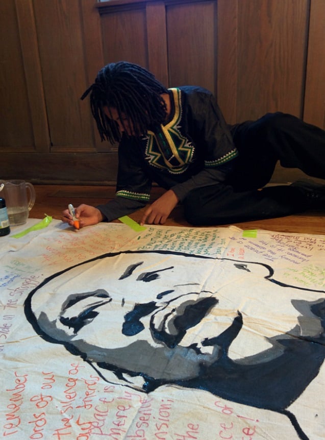 One of the event’s young organizers, from Village Leadership Academy, Kaleb Autman, works on a banner for the event. (Photo: Kelly Hayes)