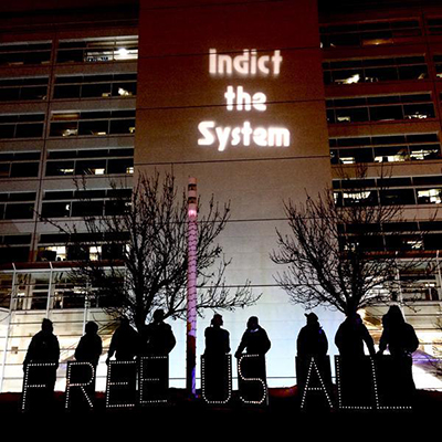 The Chicago Light Brigade using the Cook County Temporary Juvenile Detention Center as a backdrop for the night’s message. (Photo: Minku / @MinkuMedia)