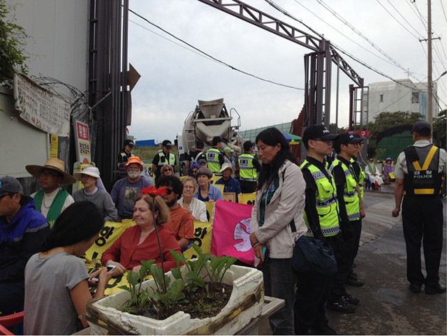 Nobel Peace laureate Mairead Maguire, Ann Wright, Catholic sisters and other Gangjeong activists after having been lifted up and carried in chairs out of the road to allow steady stream of concrete trucks to enter the naval base. (Photo: Courtesy of Ann Wright)