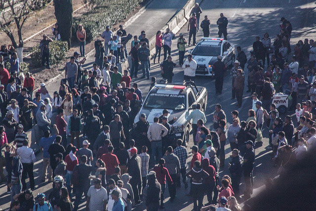 A crowd forms around a police vehicle at a No Al Gasolinazo protest in Nogales, Sonora, Mexico.