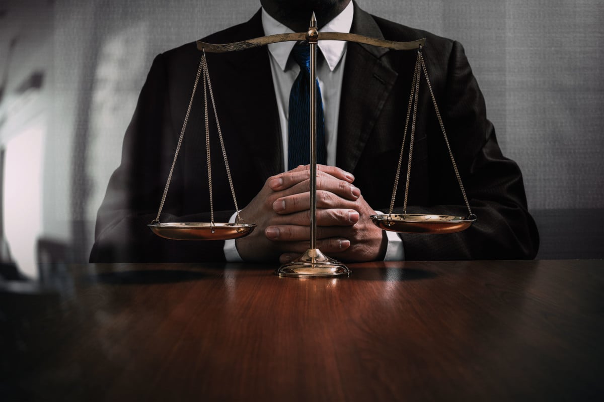 Lawyer seated behind scales of justice