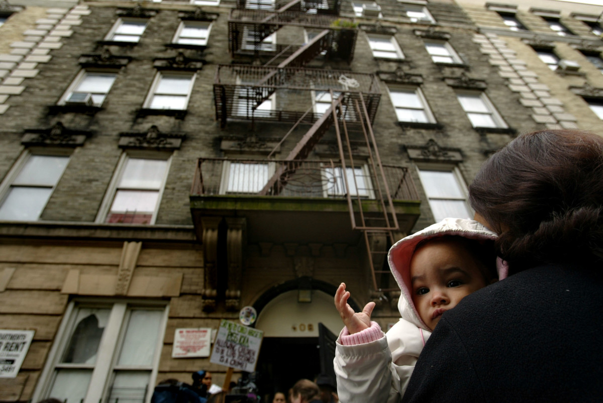 Nine-month-old Alyza Guzman is held by her mother in front of their lead contaminated apartment building October 22, 2003 in New York City.
