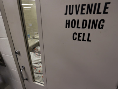 A sleeping detainee is see through the window of holding cell at a US Customs and Border Protection processing facility, Wednesday, June 18, 2014, in Brownsville, Texas.