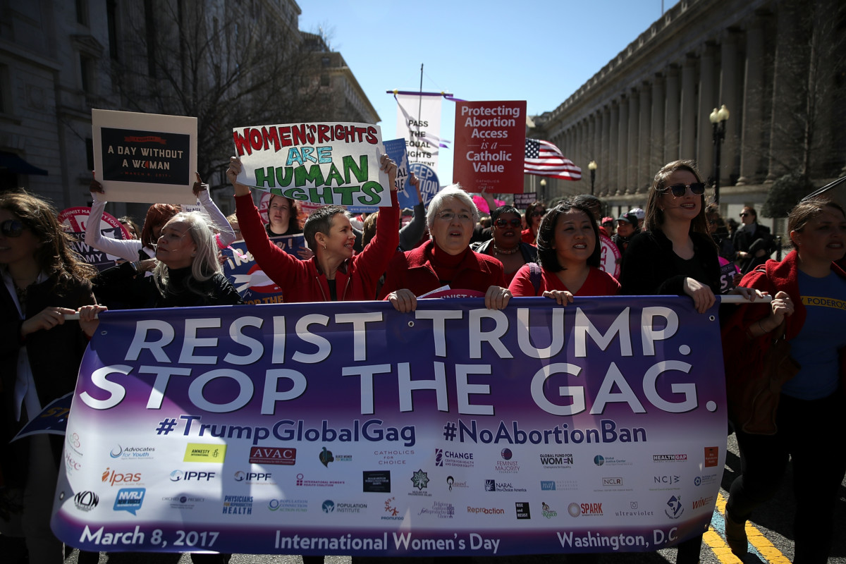 Protesters hold signs as they march to the White House during a march and rally to support family planning programs and protest the White House global gag rule on March 8, 2017, in Washington, DC.
