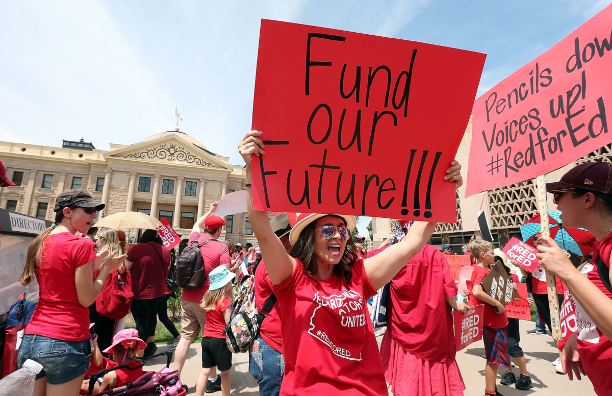 An Arizona teacher holds up a sign in front of the State Capitol during a #REDforED rally on April 26, 2018, in Phoenix, Arizona.