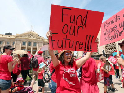 An Arizona teacher holds up a sign in front of the State Capitol during a #REDforED rally on April 26, 2018, in Phoenix, Arizona.