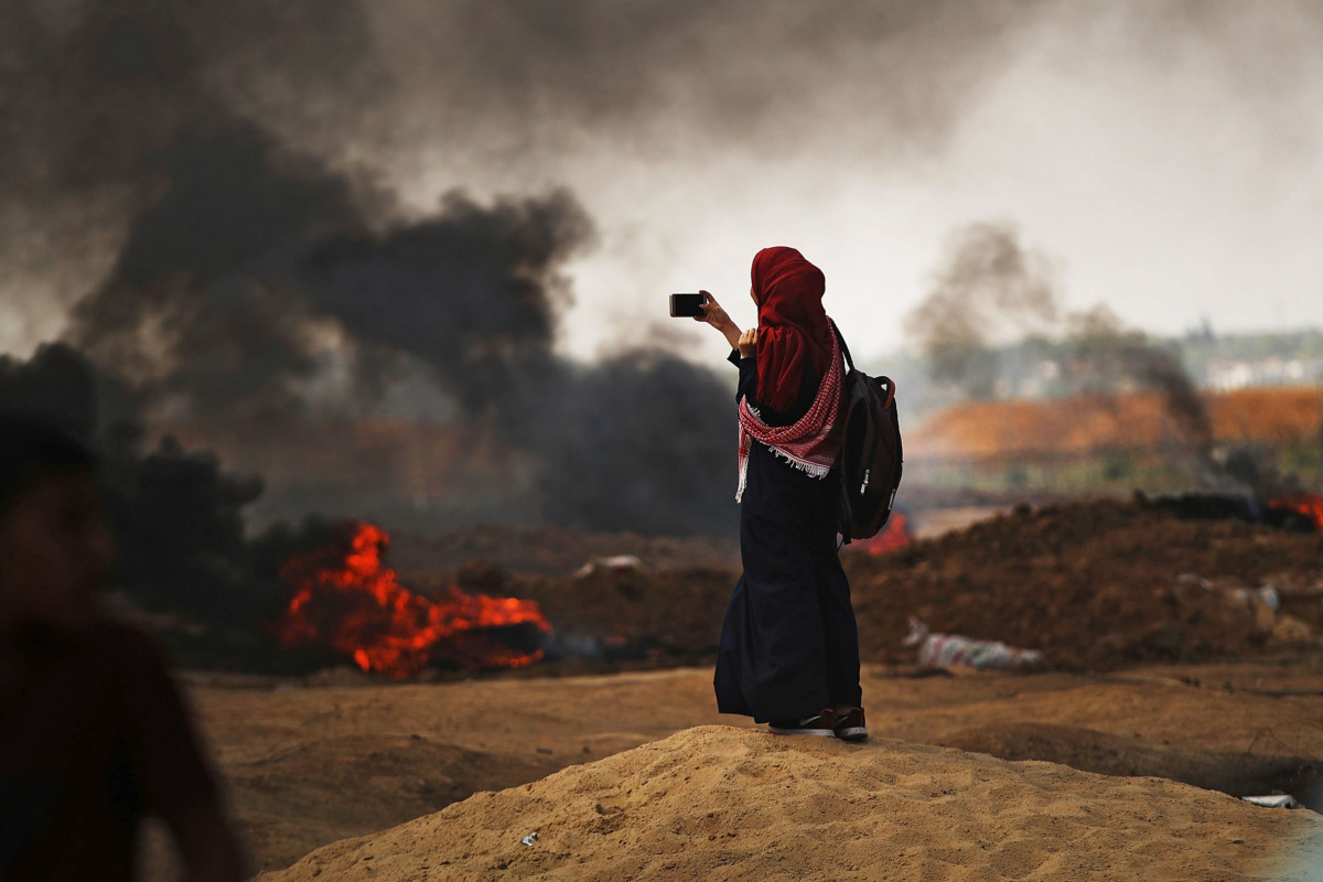 A Palestinian woman documents the situation at the border fence with Israel as mass demonstrations continue on May 14, 2018, in Gaza City, Gaza.