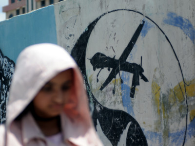 A girl walks by a US drone graffiti painted on a wall during a campaign against using US drones in Yemen on May 31, 2018, in Sana’a, Yemen.