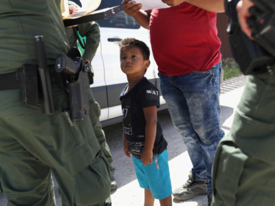 A boy and father from Honduras are taken into custody by US Border Patrol agents near the US-Mexico Border on June 12, 2018, near Mission, Texas. The asylum seekers were then sent to a US Customs and Border Protection processing center for possible separation.