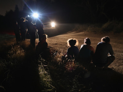 A US Border Patrol vehicle illuminates a group of Central American asylum seekers before taking them into custody near the US-Mexico border on June 12, 2018 in McAllen, Texas.