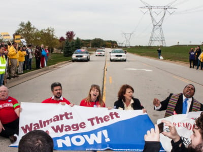 Protesters, including clergy members, stage a sit-down protest to block the entrance of the Walmart distribution center at a rally for Warehouse Workers Justice, October 1, 2012