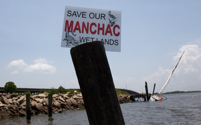 A sailboat damaged on a windy day tied up at a boat launch next to the fire department in Manchac.