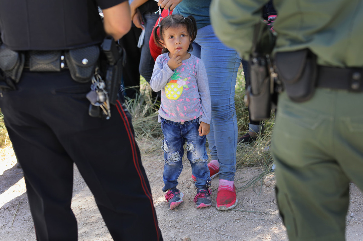 A Mission Police Dept. officer and a US Border Patrol agent watch over a group of Central American asylum seekers before taking them into custody on June 12, 2018 near McAllen, Texas.