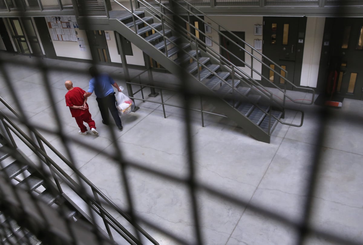 A guard escorts an immigrant detainee from his 'segregation cell' back into the general population at the Adelanto Detention Facility on November 15, 2013 in Adelanto, California.