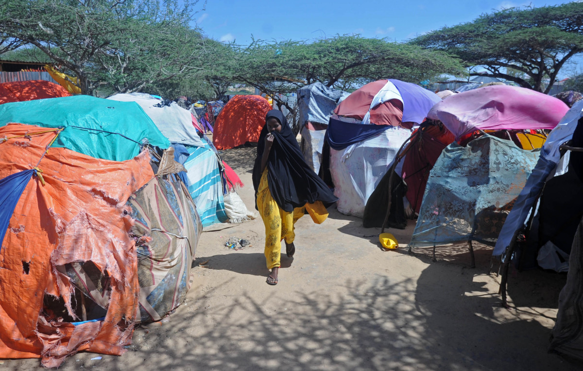 A displaced Somali woman walks past makeshift tents on May 24, 2017 at a camp in the Garasbaley area on the outskirts of the capital Mogadishu, where people converge after fleeing their homes due to the dire drought that hits the country.