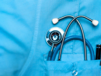 Stethoscope and pen in doctor robe pocket.