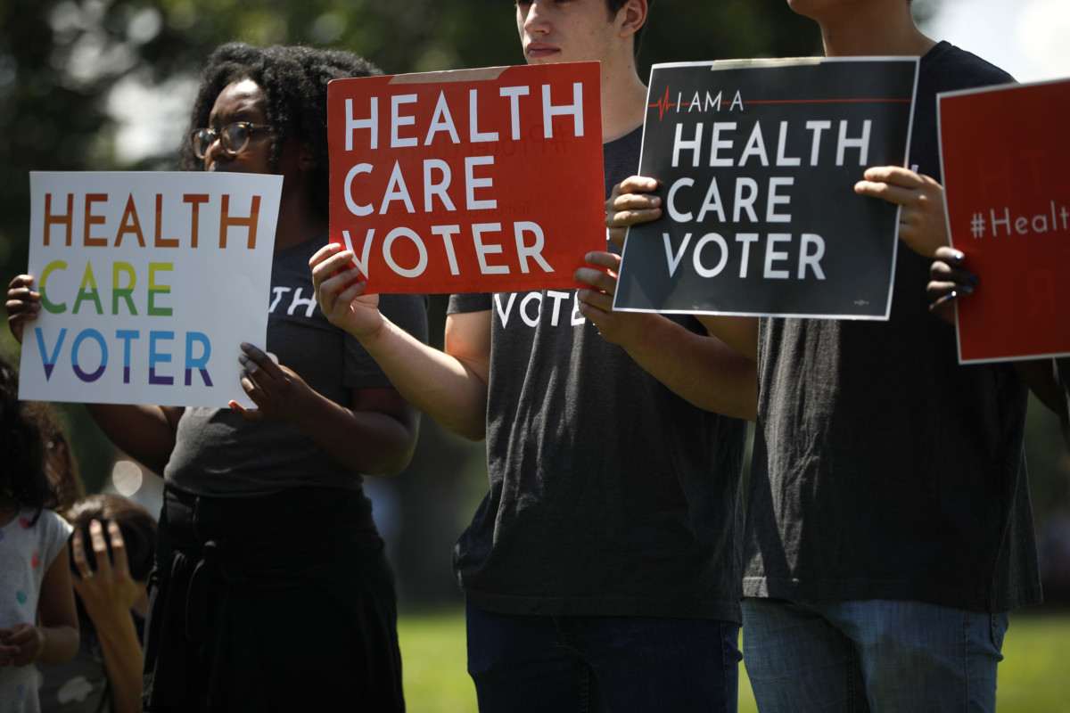 Demonstrators hold signs as Democratic leaders speak with reporters outside the US Capitol on June 26, 2018, in Washington, DC.