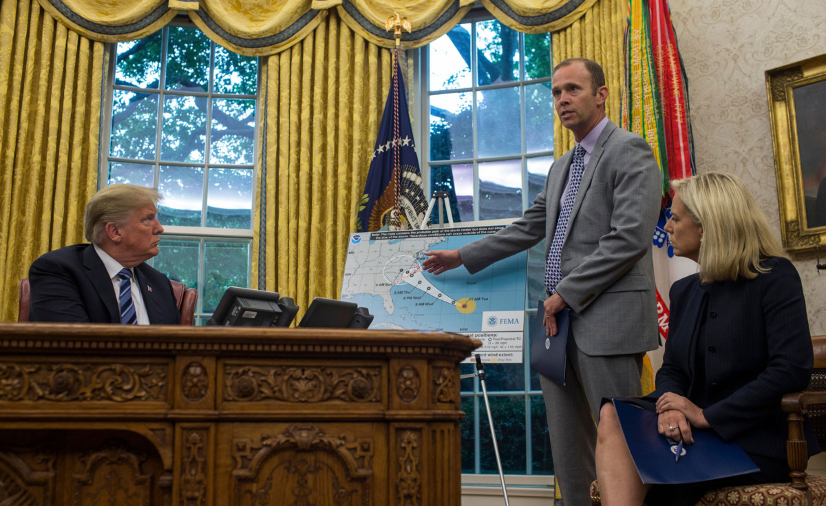 Brock Long, administrator of the Federal Emergency Management Agency, speaks in the Oval Office at the White House September 11, 2018, in Washington, DC, after briefing President Trump on Hurricane Florence. Seated at right is US Secretary of Homeland Security Kirstjen Nielsen.