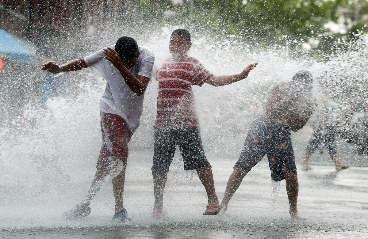 Children play in water sprayed from a fire hydrant during an early summer heat wave in the Bronx borough of New York City.