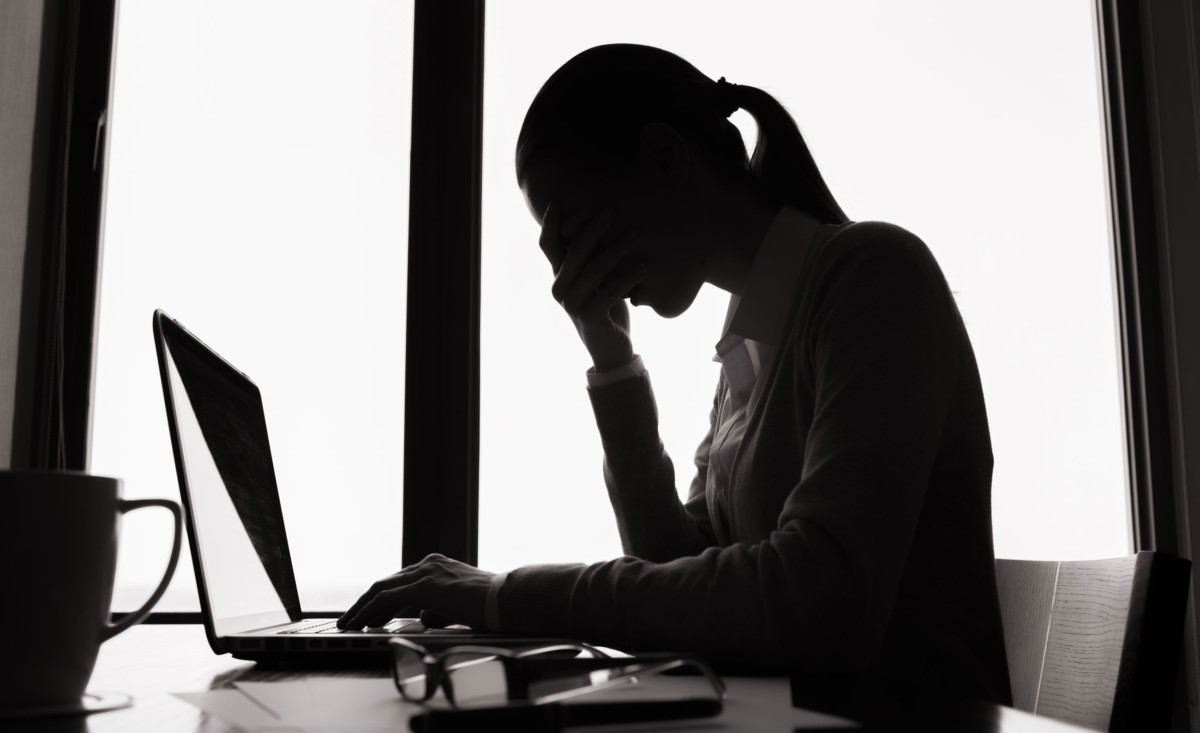 Woman in silhouette, holding forehead