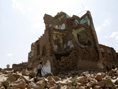 A boy walks by a house destroyed in an airstrike carried out by a Saudi-led coalition warplane in 2018 in Sana'a, Yemen.