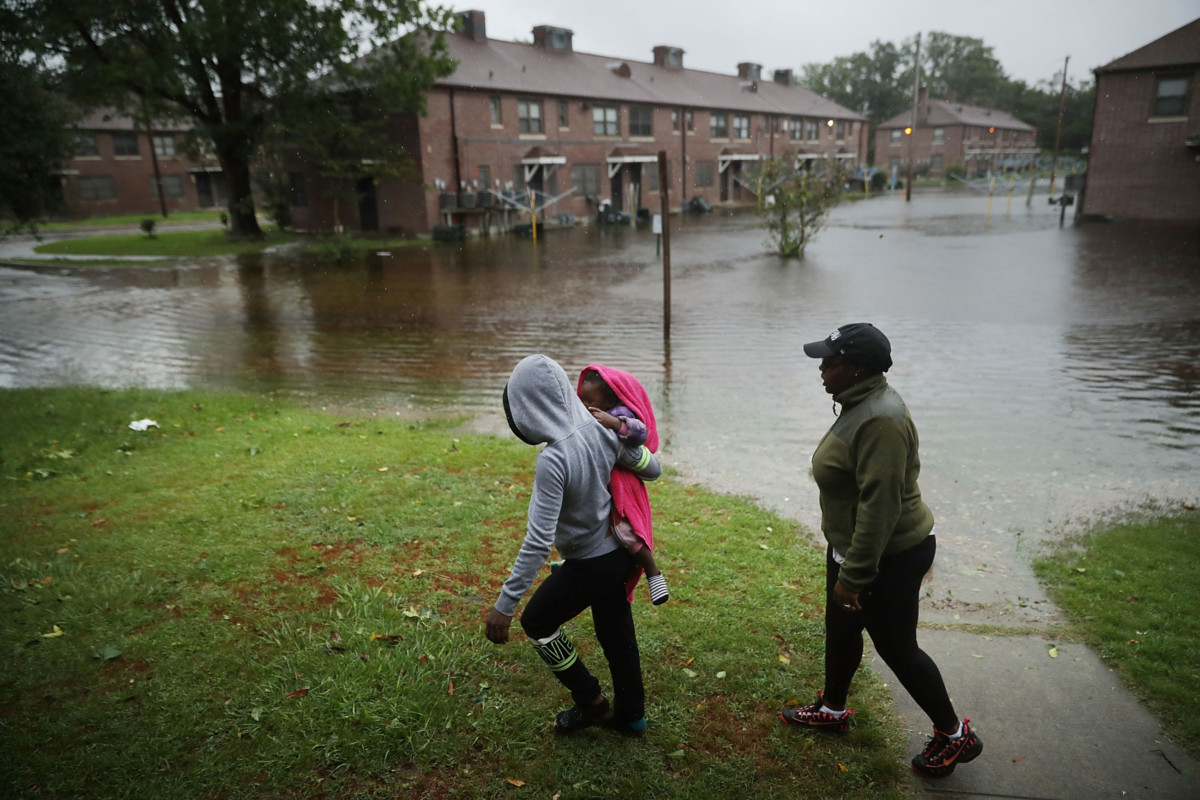 Diamond Dillahunt, 2-year-old Ta-Layah Koonce and Shkoel Collins survey the flooding at the Trent Court public housing apartments after the Neuse River topped its banks during Hurricane Florence, September 13, 2018, in New Bern, North Carolina.