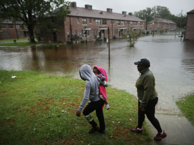 Diamond Dillahunt, 2-year-old Ta-Layah Koonce and Shkoel Collins survey the flooding at the Trent Court public housing apartments after the Neuse River topped its banks during Hurricane Florence, September 13, 2018, in New Bern, North Carolina.