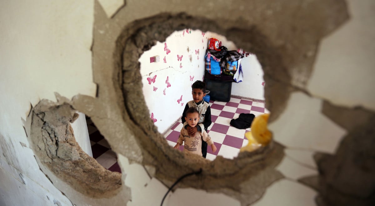Displaced Yemeni children from the Hodeidah province are pictured on September 30, 2018, through a hole in a damaged house where they have been living with other displaced families in the southwestern Yemeni city of Taez. The conflict has triggered what the UN describes as the world's worst humanitarian crisis, with 22 million people in need of humanitarian aid.