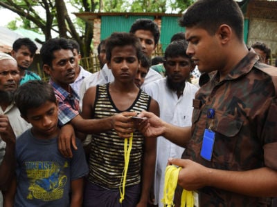 Rohingya refugees receive new ID cards from a soldier at the entrance to the Bangladeshi government registration office at the Kutupalong refugee camp near Ukhia on September 22, 2017.