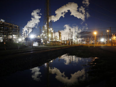 Emissions from an oil refinery are reflected in a street puddle at dusk in Texas.